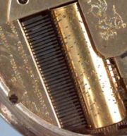 Close-up of the musical comb and pinned cylinder barrel — showing the fine teeth of the comb and the precisely placed pins on the brass cylinder